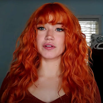 La Sylphide ginger red synthetic wig with long wavy hair and bangs styled on a woman