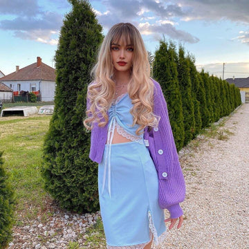 HAIRCUBE blonde synthetic wig with bangs styled in long loose curls on a woman outdoors