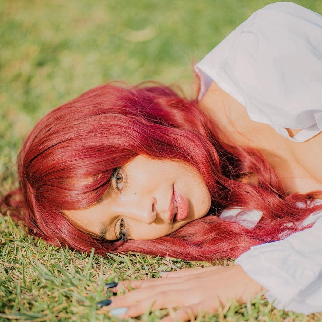 HAIRCUBE 18 inch red wine wig worn by woman lying on grass with soft curls and side part