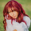 HAIRCUBE 18 inch red wine wig with soft waves and curtain bangs worn by woman outdoors