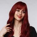HAIRCUBE 18 inch red wine wig with long wavy hair and full bangs styled on a smiling woman
