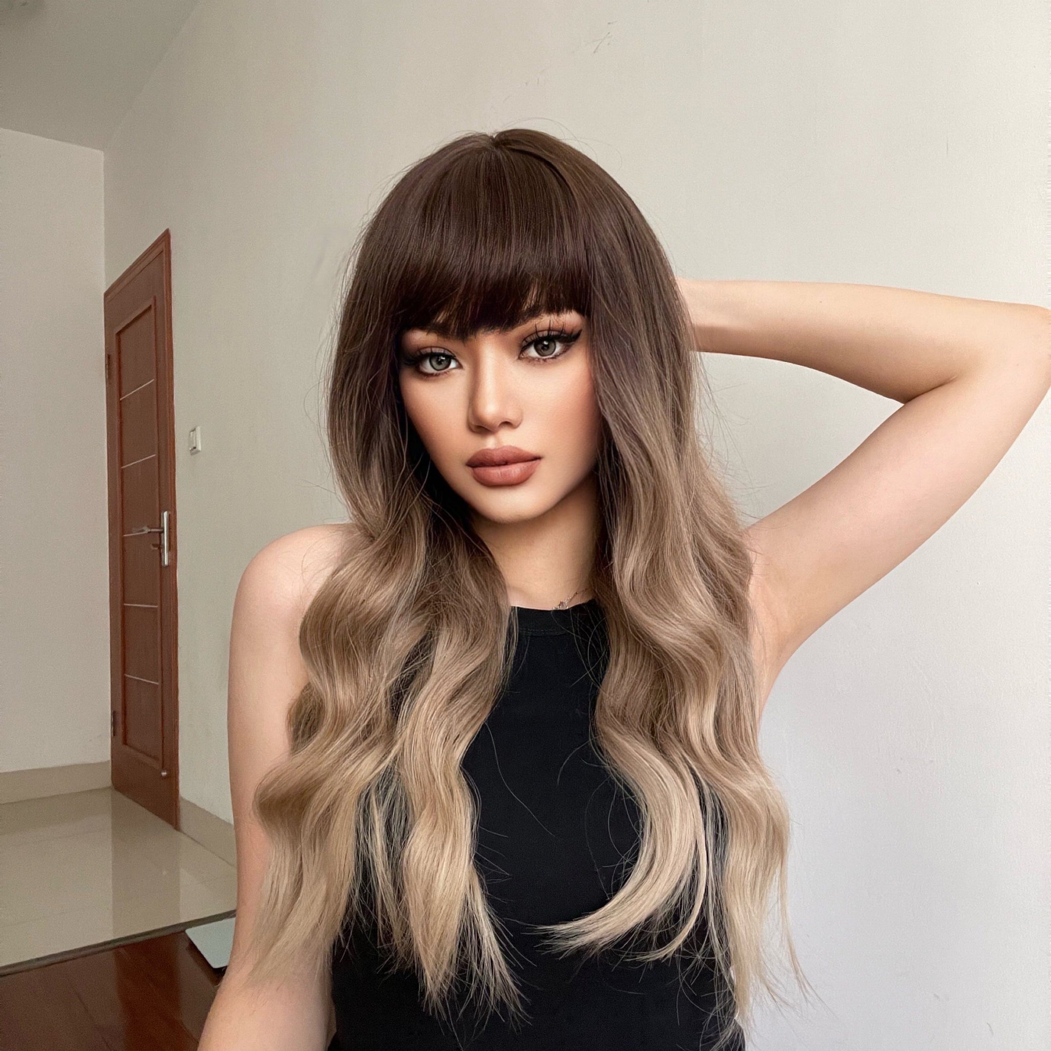 HAIRCUBE 23 inch ombre ash blonde wig with bangs and wavy hair on model wearing black sleeveless top