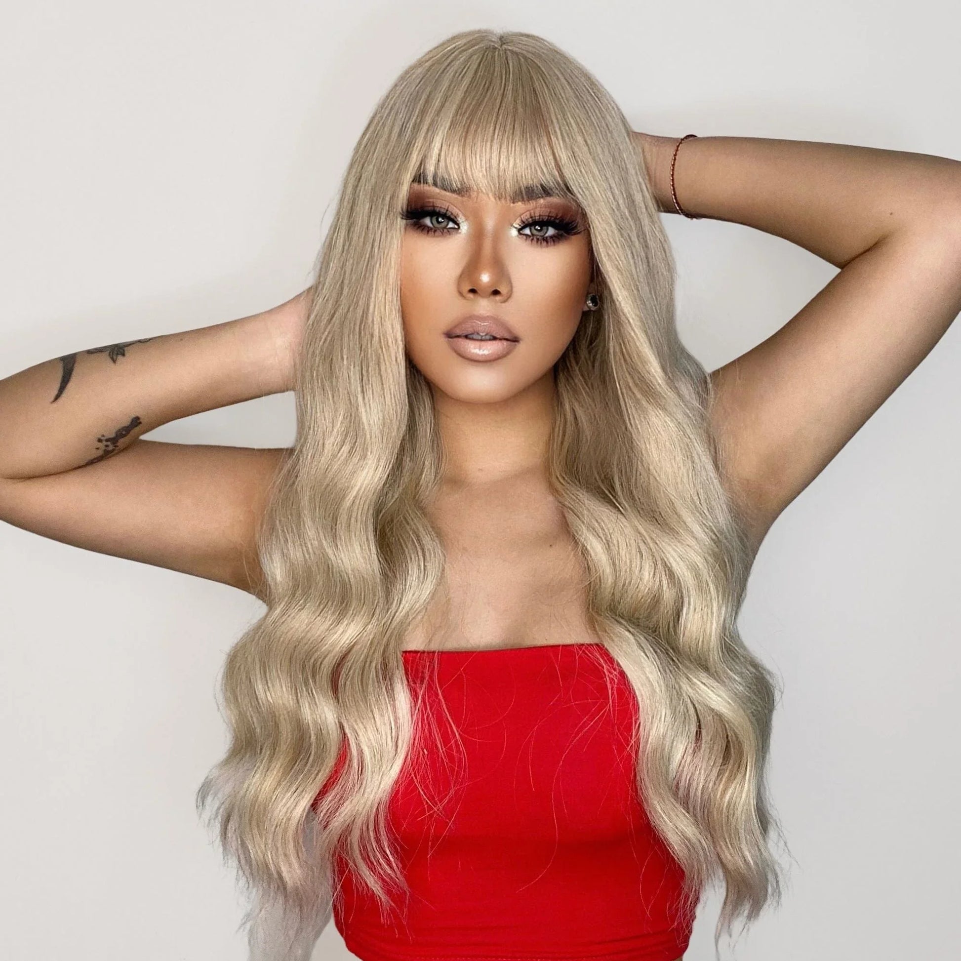 oneNonly 26 inch synthetic wig with bangs in blonde long wavy style worn by woman