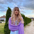 Blonde synthetic wig with bangs styled in loose curls worn by model outdoors