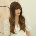 HAIRCUBE dark brown long curly synthetic wig styled with bangs on a model wearing white blouse