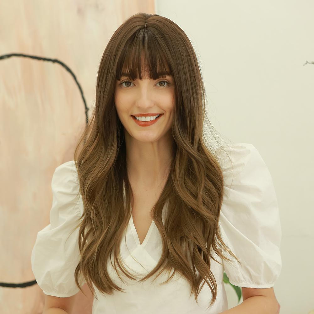 HAIRCUBE dark brown long curly synthetic wig worn by woman with bangs and white puff sleeve top