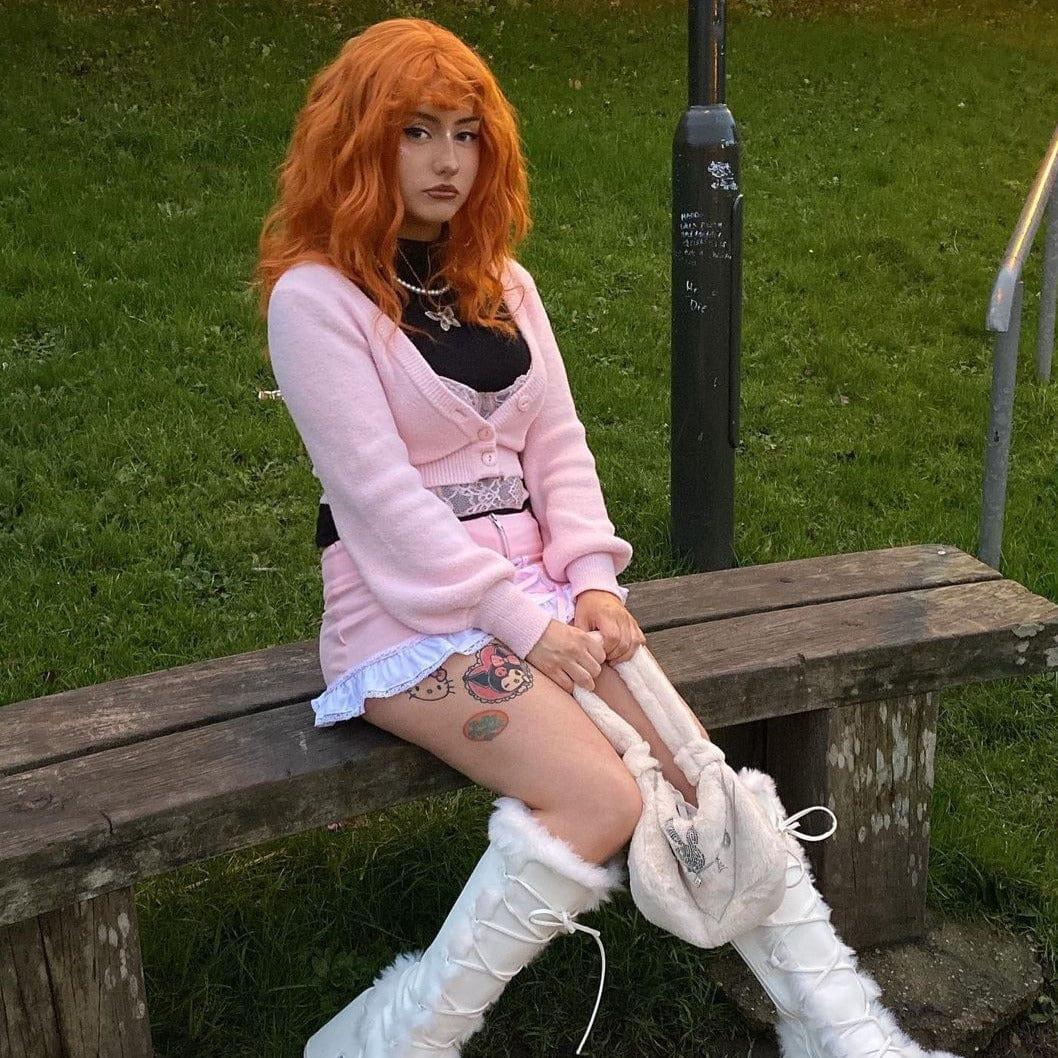 La Sylphide ginger red synthetic wig worn by woman sitting on wooden bench outdoors