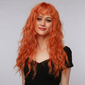 La Sylphide ginger red synthetic wig with long wavy hair styled with bangs on smiling woman