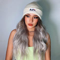 HAIRCUBE smokey grey synthetic wig with long wavy strands worn with a white beanie