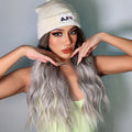 HAIRCUBE smokey grey synthetic wig styled with loose waves worn by woman in white beanie