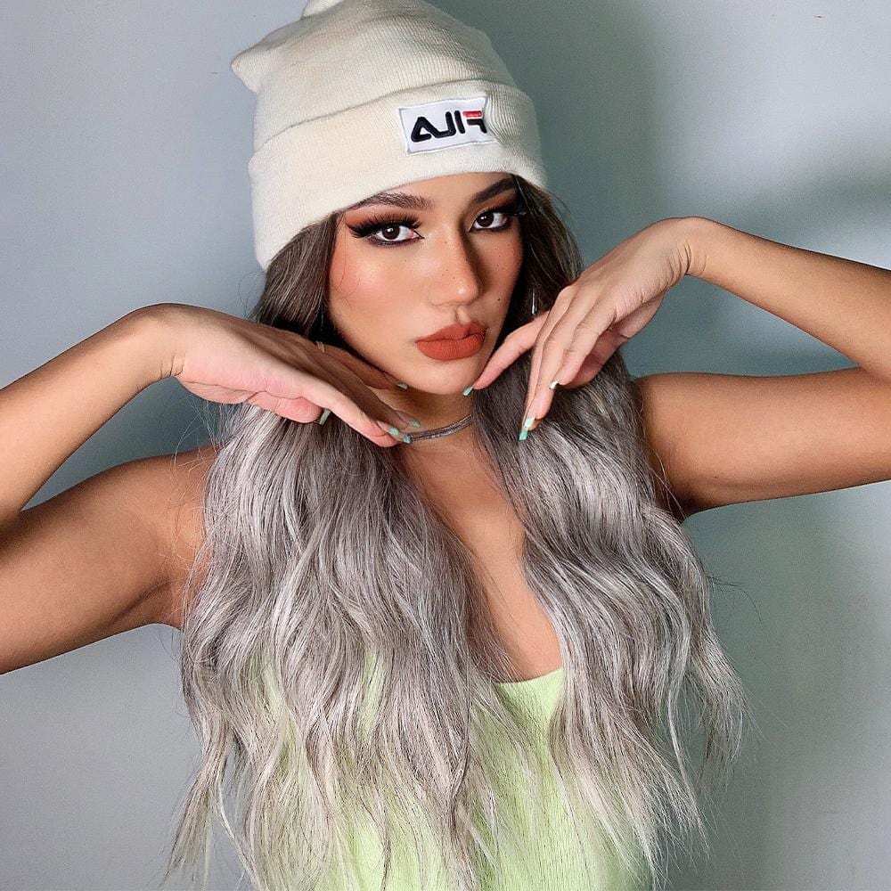 HAIRCUBE smokey grey synthetic wig styled with loose waves worn by woman in white beanie