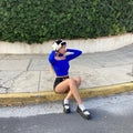 HAIRCUBE straight synthetic wig with bangs worn by woman sitting on curb in blue top and black shorts