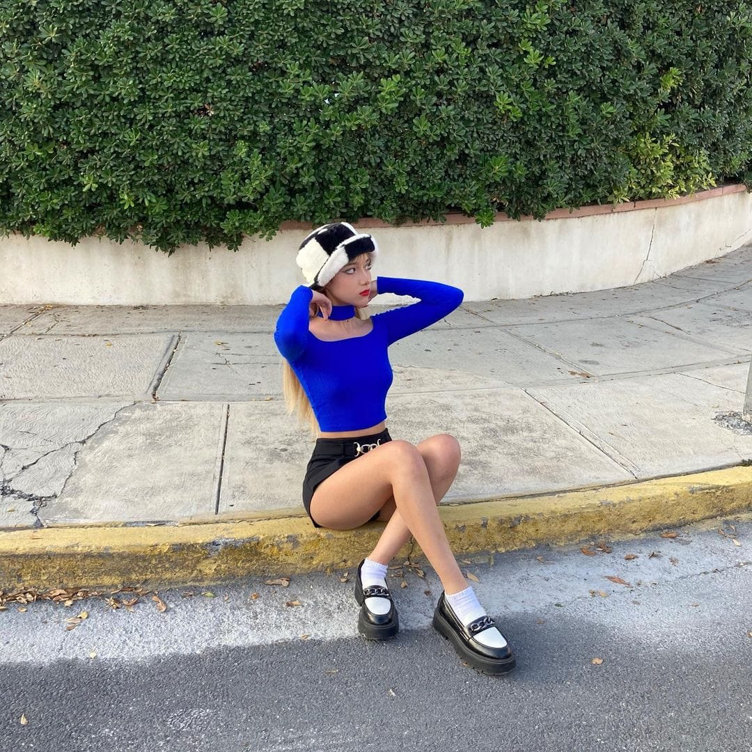 HAIRCUBE straight synthetic wig with bangs worn by woman sitting on curb in blue top and black shorts