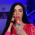 Woman wearing 23 inch free part synthetic wig by HAIRCUBE with long straight black hair holding a lighter