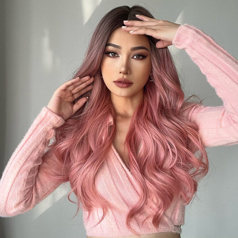 23 inch pink synthetic wig by HAIRCUBE styled with loose waves on a model wearing a pink sweater