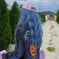 HAIRCUBE mermaid blue synthetic wig with long wavy hair worn under a pink cap outdoors