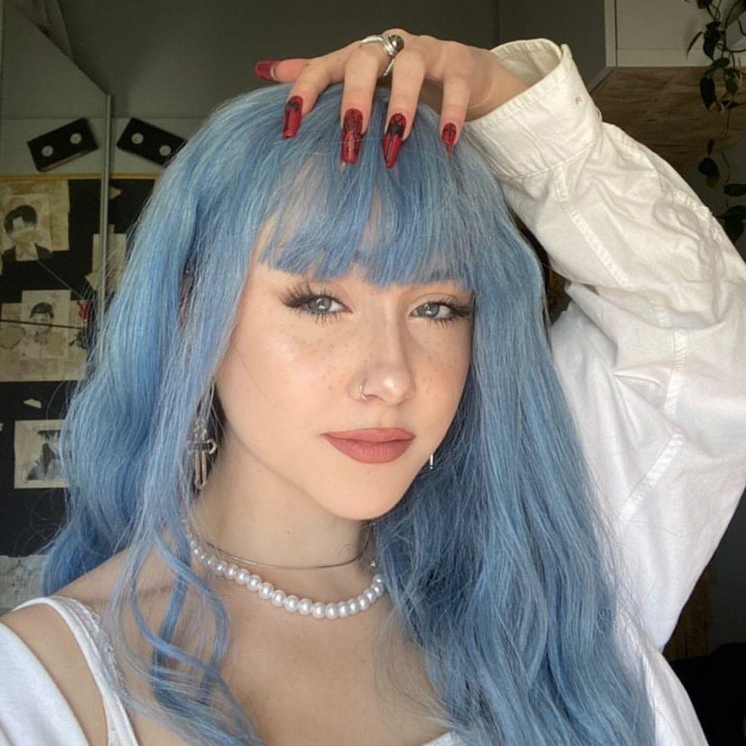 HAIRCUBE mermaid blue synthetic wig worn by woman with long wavy hair and bangs