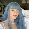 HAIRCUBE mermaid blue synthetic wig styled with bangs on woman wearing white top and pearl necklace