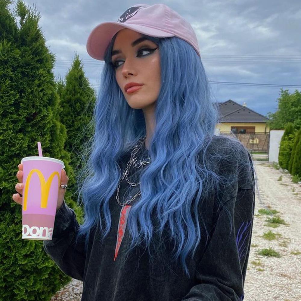 HAIRCUBE mermaid blue synthetic wig with long wavy hair styled on a woman wearing a pink cap